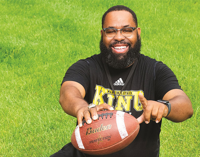 Rickey holding football on green field