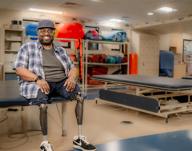 Alonzo with prosthetic legs in therapy room