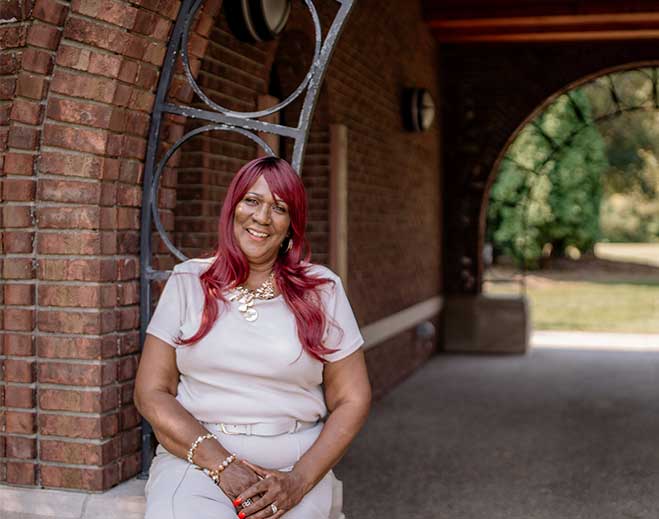 Cynthia seated near brick archway outdoors