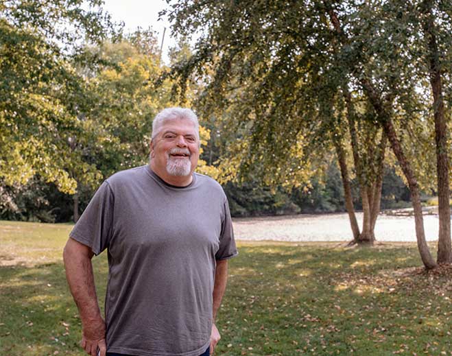 Dave standing in park near lake and trees