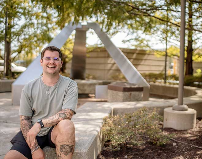Max sitting outdoors near modern sculpture