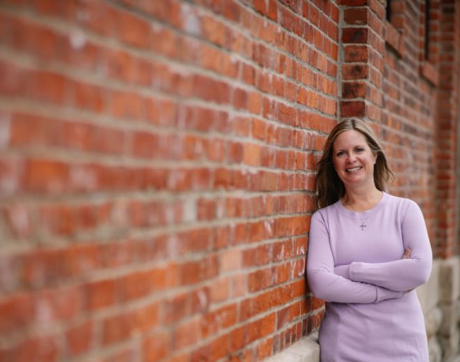 Andrea standing against brick wall outdoors
