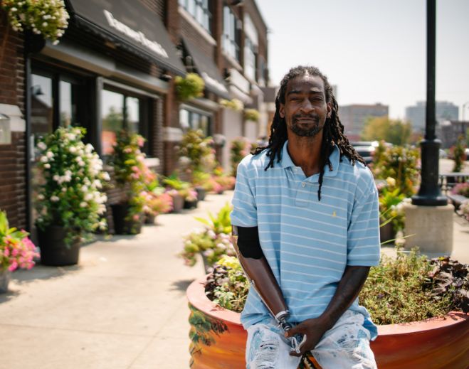 Raymond seated outdoors on city sidewalk planter